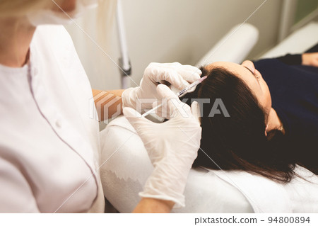 Girl has hair problems. Mesotherapy procedure. Doctor makes an injection against hair loss... 94800894