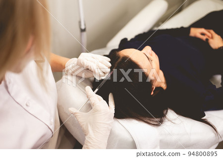 Girl has hair problems. Mesotherapy procedure. Doctor makes an injection against hair loss... 94800895