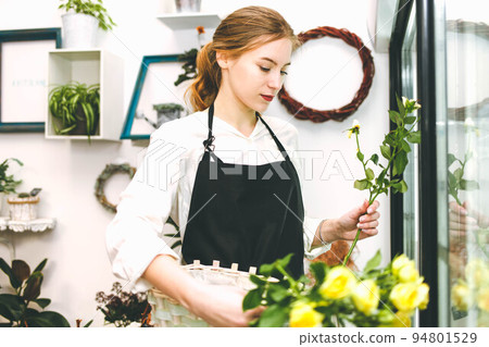 Florist takes flowers out of the fridge. Flower seller chooses flowers for future bouquet. Florist takes flowers out of the fridge. Flower seller chooses flowers for future bouquet. 94801529