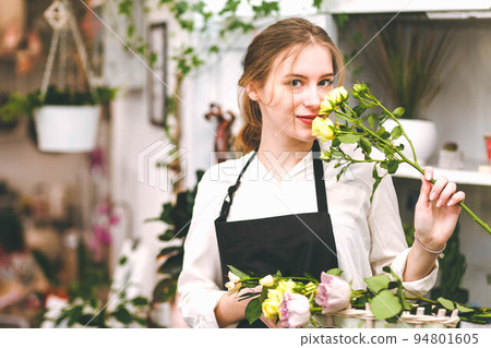 Portrait of a florist girl with flowers in her hands in a flower boutique.. Portrait of a florist girl with flowers in her hands in a flower boutique.. 94801605