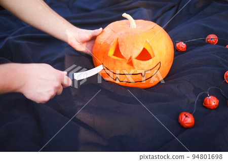Hand cutting an orange pumpkin with a knife... Hand cutting an orange pumpkin with a knife... 94801698