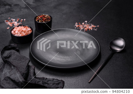 Empty black plate over dark stone background with free space. Top view Empty black plate over dark stone background with free space. Top view 94804210
