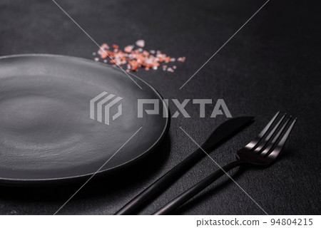 Empty black plate over dark stone background with free space. Top view Empty black plate over dark stone background with free space. Top view 94804215