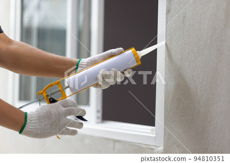 Construction worker using silicone sealant caulk the outside window frame. Construction worker using silicone sealant caulk the outside window frame. 94810351