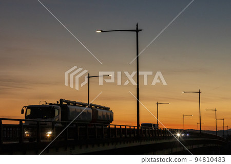A truck running on a national highway at dusk 94810483