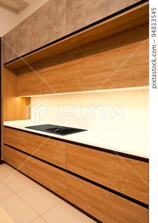 Modern brown wood oak kitchen cabinet equipment and granite black sink in a home 94813545