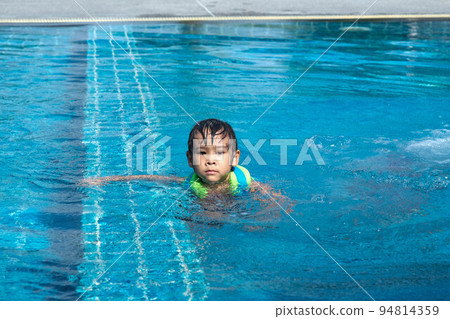 Little girl plays in the outdoor swimming pool of tropical resort during family summer vacation. Kids learning to swim. Healthy Summer Activities for Kids. Little girl plays in the outdoor swimming pool of tropical resort during family summer vacation. Kids learning to swim. Healthy Summer Activities for Kids. 94814359