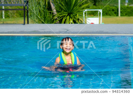Little girl plays in the outdoor swimming pool of tropical resort during family summer vacation. Kids learning to swim. Healthy Summer Activities for Kids. Little girl plays in the outdoor swimming pool of tropical resort during family summer vacation. Kids learning to swim. Healthy Summer Activities for Kids. 94814360