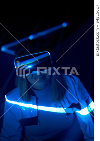 Woman is using virtual reality headset to access in metaverse. 94815617