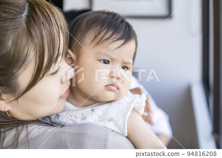 An infant who is hugged with a troubled expression 94816208