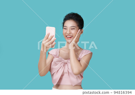Image of emotional positive young pretty woman posing isolated over blue wall background take selfie by mobile phone showing peace gesture. 94816394