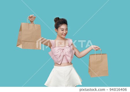A young pretty girl shows off a large brown paper bag on a cyan background. A young pretty girl shows off a large brown paper bag on a cyan background. 94816406