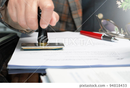 hand holding rubber stamper on white paperwork hand holding rubber stamper on white paperwork 94818433