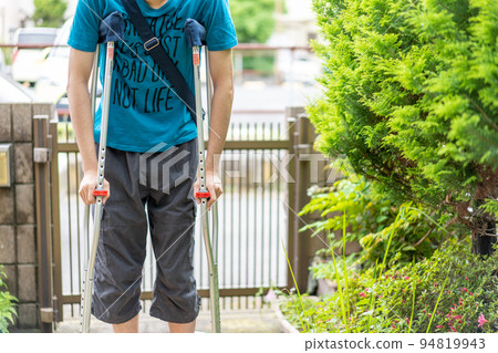 Man walking with crutches at the front door 94819943