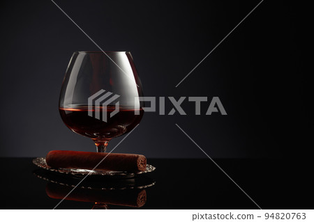 Snifter of brandy and cigar on a black background. Snifter of brandy and cigar on a black background. 94820763
