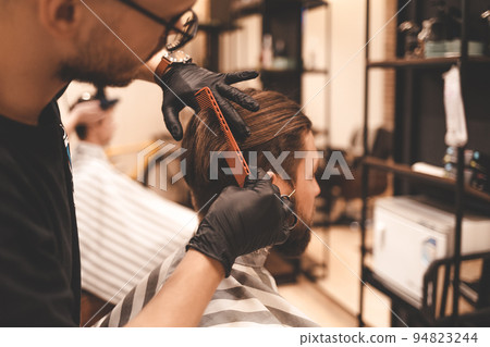 barber makes a haircut for a young hipster.. barber makes a haircut for a young hipster.. 94823244