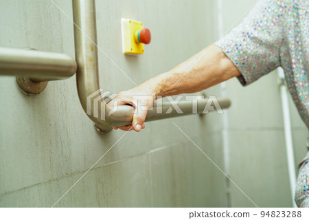 Asian elderly old woman patient use toilet support rail in bathroom, handrail safety grab bar, security in nursing hospital. 94823288