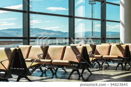 Airport terminal waiting area with empty chairs Airport terminal waiting area with empty chairs 94823645