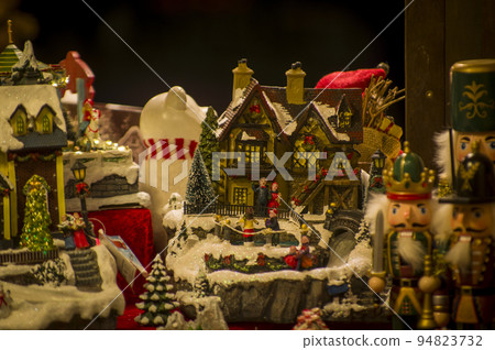 Advent Bazaar Stalls with glass, wooden, ceramic christmas souvenirs in shops. Close up of festive decorations for tree in winter street night market during new year's holiday. Illuminated fair kiosk 94823732