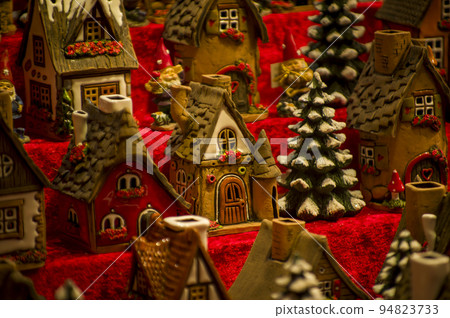 Advent Bazaar Stalls with glass, wooden, ceramic christmas souvenirs in shops. Close up of festive decorations for tree in winter street night market during new year's holiday. Illuminated fair kiosk 94823733