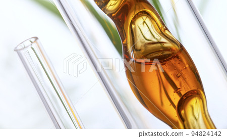 Getting natural oil from natural substances and flowers. Yellow oil flows in a spiral. Getting natural oil from natural substances and flowers. Yellow oil flows in a spiral. 94824142