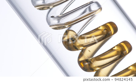 Getting natural oil from natural substances and flowers. Yellow oil flows in a spiral. Getting natural oil from natural substances and flowers. Yellow oil flows in a spiral. 94824145