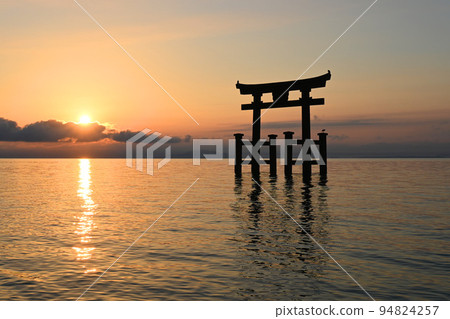 The Otorii gate standing in the lake at sunrise at Shirahige Shrine in Shiga Prefecture is mysterious. 94824257