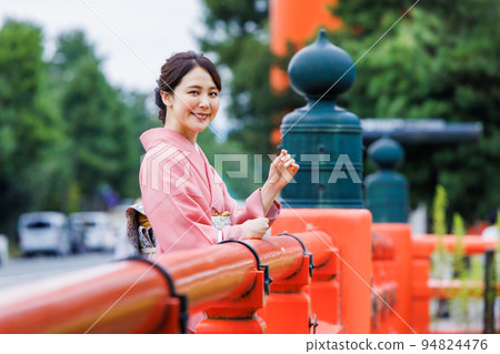 A woman in a kimono enjoying sightseeing in Kyoto in front of Otorii 94824476