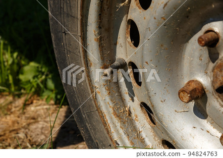 capped schrader valve and stem on a vehicle tire with rim. old rusty wheel in the sunlight. Close-up capped schrader valve and stem on a vehicle tire with rim. old rusty wheel in the sunlight. Close-up 94824763