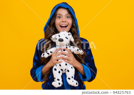 Excited kid happy smiling in hooded bathrobe holding plush toy yellow background, childhood 94825763