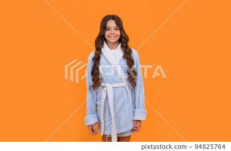 Happy girl child smiling in blue towelling bathrobe orange background, homewear 94825764