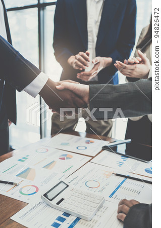 Successful businessmen handshaking after good deal at meeting room 94826472