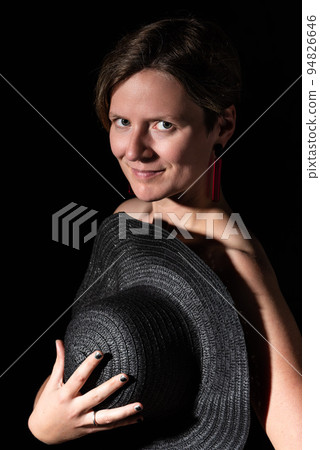 Thirty year old white woman posing in a studio with a black hat Thirty year old white woman posing in a studio with a black hat 94826646