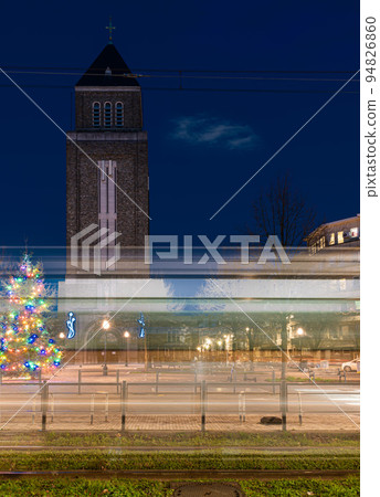 Jette, Brussels Capital Region, Belgium, Light trails of a tramway at the Charles Woeste Avenue during the blue hour with the church tower in the background Jette, Brussels Capital Region, Belgium, Light trails of a tramway at the Charles Woeste Avenue during the blue hour with the church tower in the background 94826860