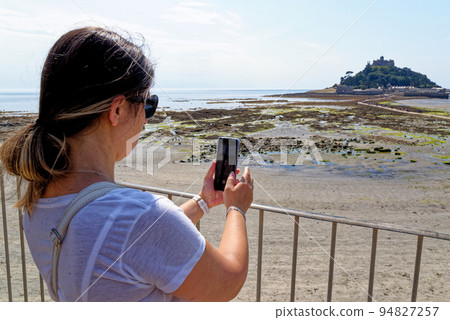 Young girl taking picture of iconic landmark of St Michael Mount - Cornwall, England Young girl taking picture of iconic landmark of St Michael Mount - Cornwall, England 94827257