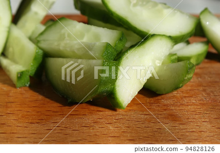 Salad of cucumbers in a plate and vegetables on a wooden table 94828126