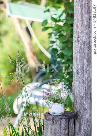 Old vintage small rustic teapot with wildflowers on garden swing background 94828197