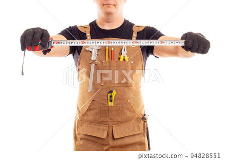 Carpenter in workers apron is holding measuring tape on white background Carpenter in workers apron is holding measuring tape on white background 94828551