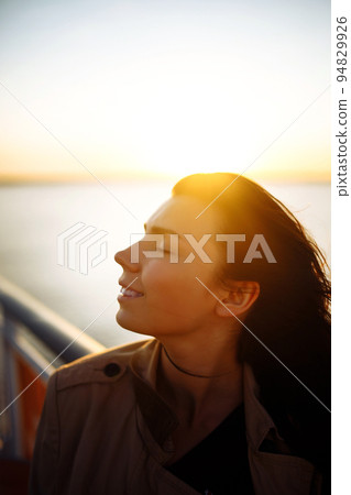 Young woman tourist enjoying sunset. Portrait of the beautiful girl close-up, wind fluttering hair 94829926