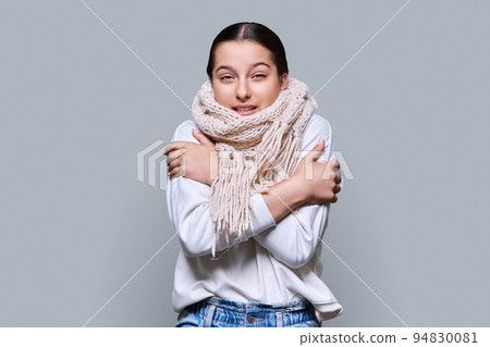 Winter portrait of young female in sweater scarf, on gray studio background Winter portrait of young female in sweater scarf, on gray studio background 94830081