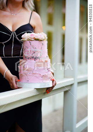 woman with two-tier pink cake with rosebuds and the inscription happy birthday. woman with two-tier pink cake with rosebuds and the inscription happy birthday. 94830818