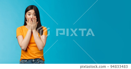 Shocked speechless stunned asian girl stare camera cover mouth palms, raise eyebrows gasping astonished, feel pitty sorry hearing bad news, stand surprised blue background wear yellow t-shirt Shocked speechless stunned asian girl stare camera cover mouth palms, raise eyebrows gasping astonished, feel pitty sorry hearing bad news, stand surprised blue background wear yellow t-shirt 94833483