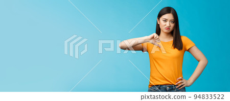 Moody unsatisfied cute asian girl picky, disliking bad restaurant food smirking displeased, grimacing disappointed show thumb down, shaking head negative judgement, stand blue background Moody unsatisfied cute asian girl picky, disliking bad restaurant food smirking displeased, grimacing disappointed show thumb down, shaking head negative judgement, stand blue background 94833522