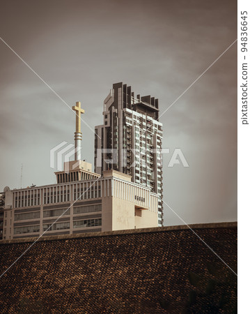 Urban view overlooking Modern tall building with Christian crucifix on Churches roof against abstract grey sky. Perfectly coexist, Copy space, Selective focus. Urban view overlooking Modern tall building with Christian crucifix on Churches roof against abstract grey sky. Perfectly coexist, Copy space, Selective focus. 94836645
