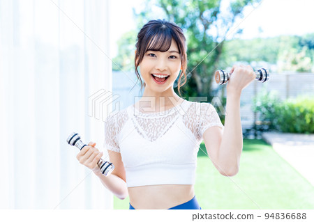 A young woman training with a dumbbell A young woman training with a dumbbell 94836688