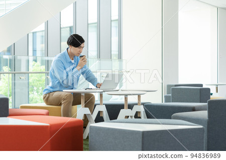 一個年輕人在辦公室的空閒空間裡用電腦工作。攝影合作“LINK FOREST” 94836989