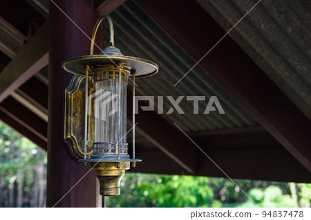 Classic golden lamp attached on wooden pillar inside home 94837478
