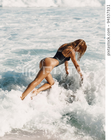 Attractive woman in swimwear posing with ocean waves 94837831