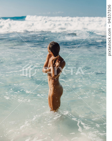 Naked woman posing at tropical beach and staying in ocean. 94837836