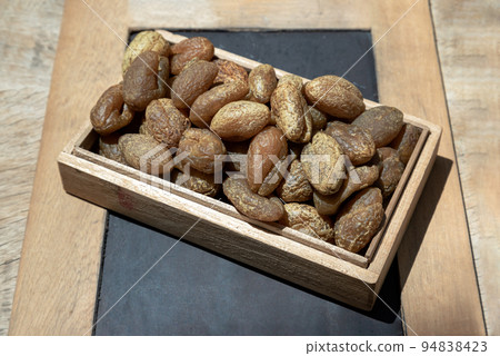 Terminalia bellerica or Terminalia chebula (Organic dry harad). Dried fruits in the wooden box. Terminalia bellerica or Terminalia chebula (Organic dry harad). Dried fruits in the wooden box. 94838423